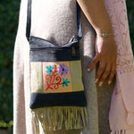 A small sling style, cross body bag with tassel/fringe at the bottom giving it a bohemian chic look.