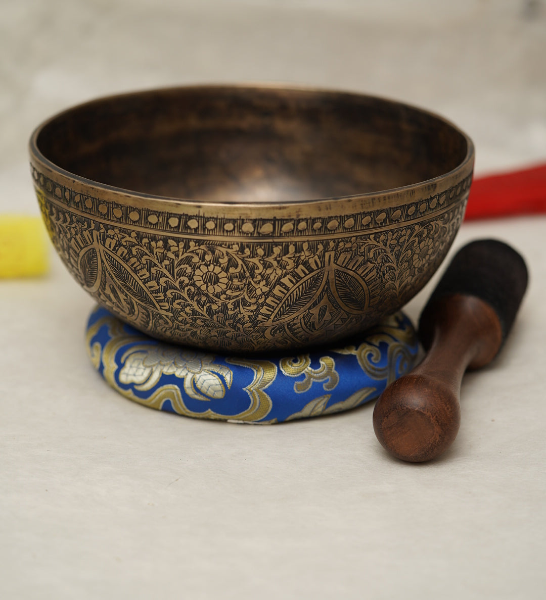 Handmade Tibetan singing bowl with flower, leaf, and vine mandala carvings,  used for meditation and sound healing.