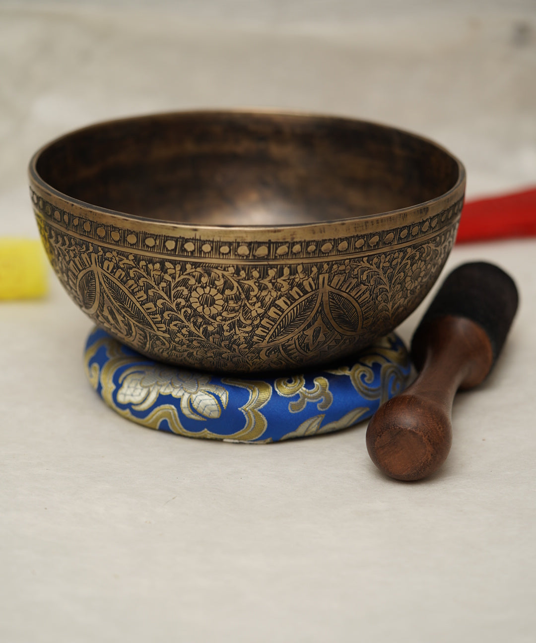 Handmade Tibetan singing bowl with flower, leaf, and vine mandala carvings,  used for meditation and sound healing.