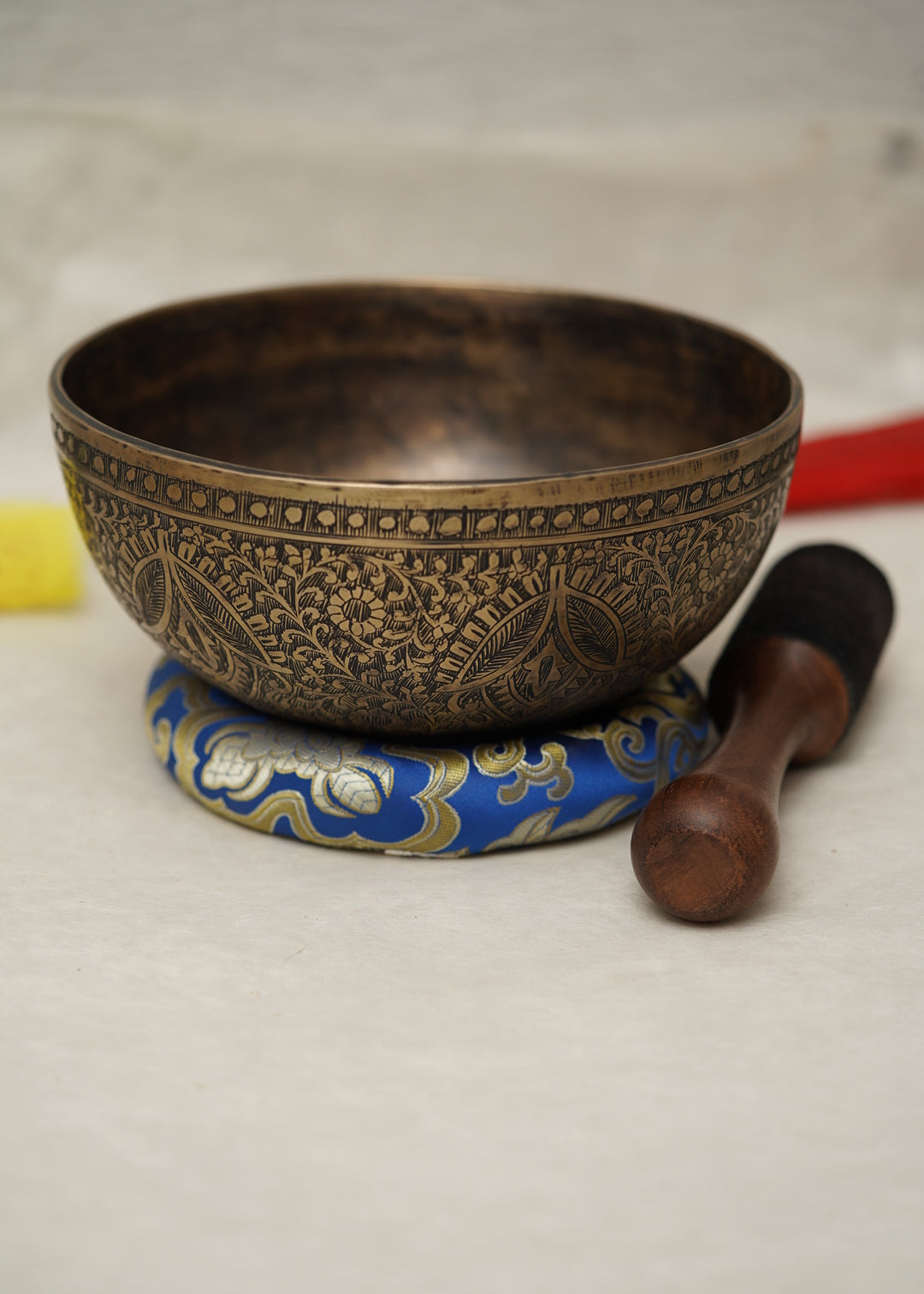 Handmade Tibetan singing bowl with flower, leaf, and vine mandala carvings,  used for meditation and sound healing.