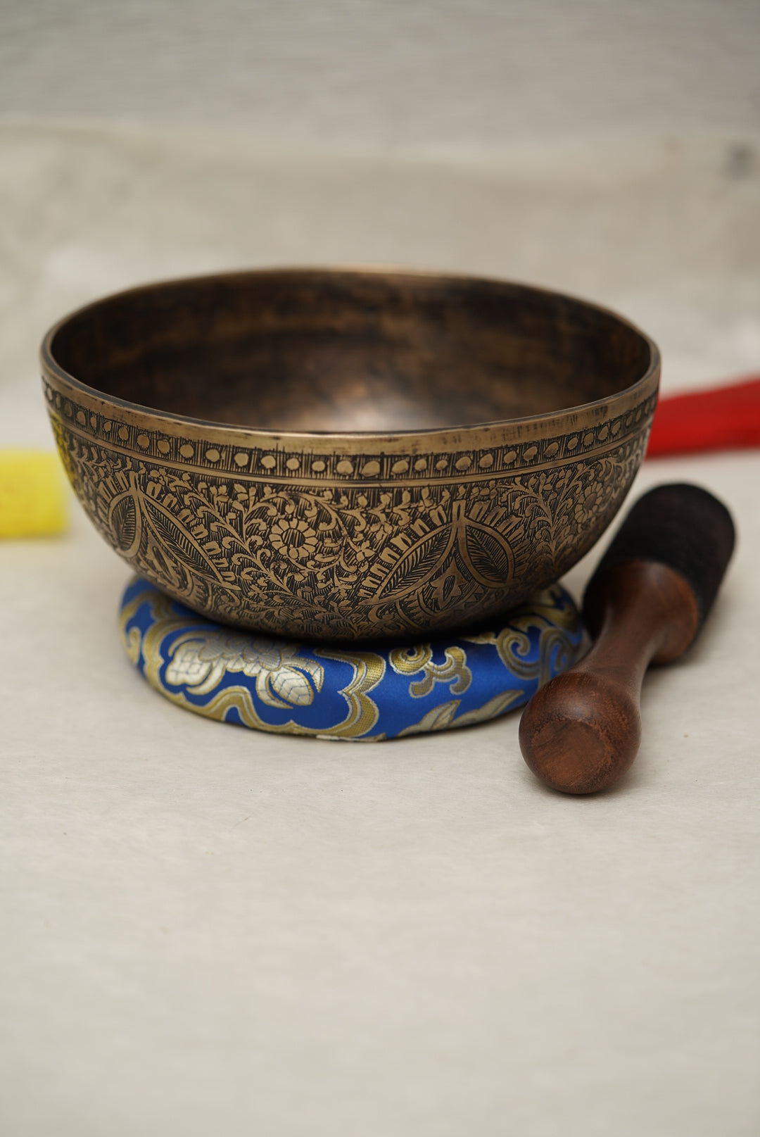 Handmade Tibetan singing bowl with flower, leaf, and vine mandala carvings,  used for meditation and sound healing.