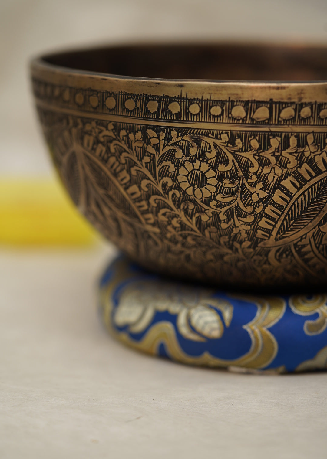 Handmade Tibetan singing bowl with flower, leaf, and vine mandala carvings,  used for meditation and sound healing.