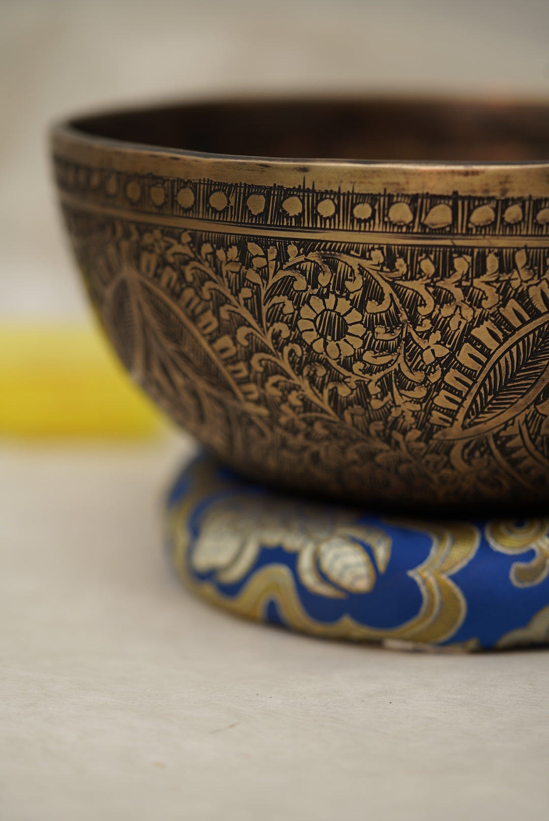 Handmade Tibetan singing bowl with flower, leaf, and vine mandala carvings,  used for meditation and sound healing.