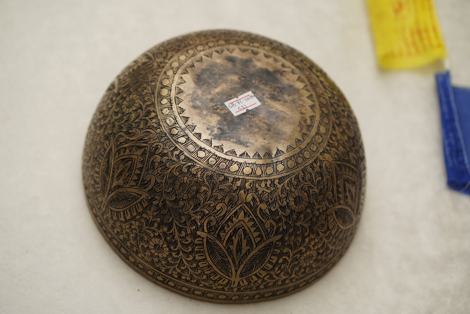 Handmade Tibetan singing bowl with flower, leaf, and vine mandala carvings,  used for meditation and sound healing.