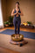 Woman in a yoga pose with a large singing bowl in a serene room.