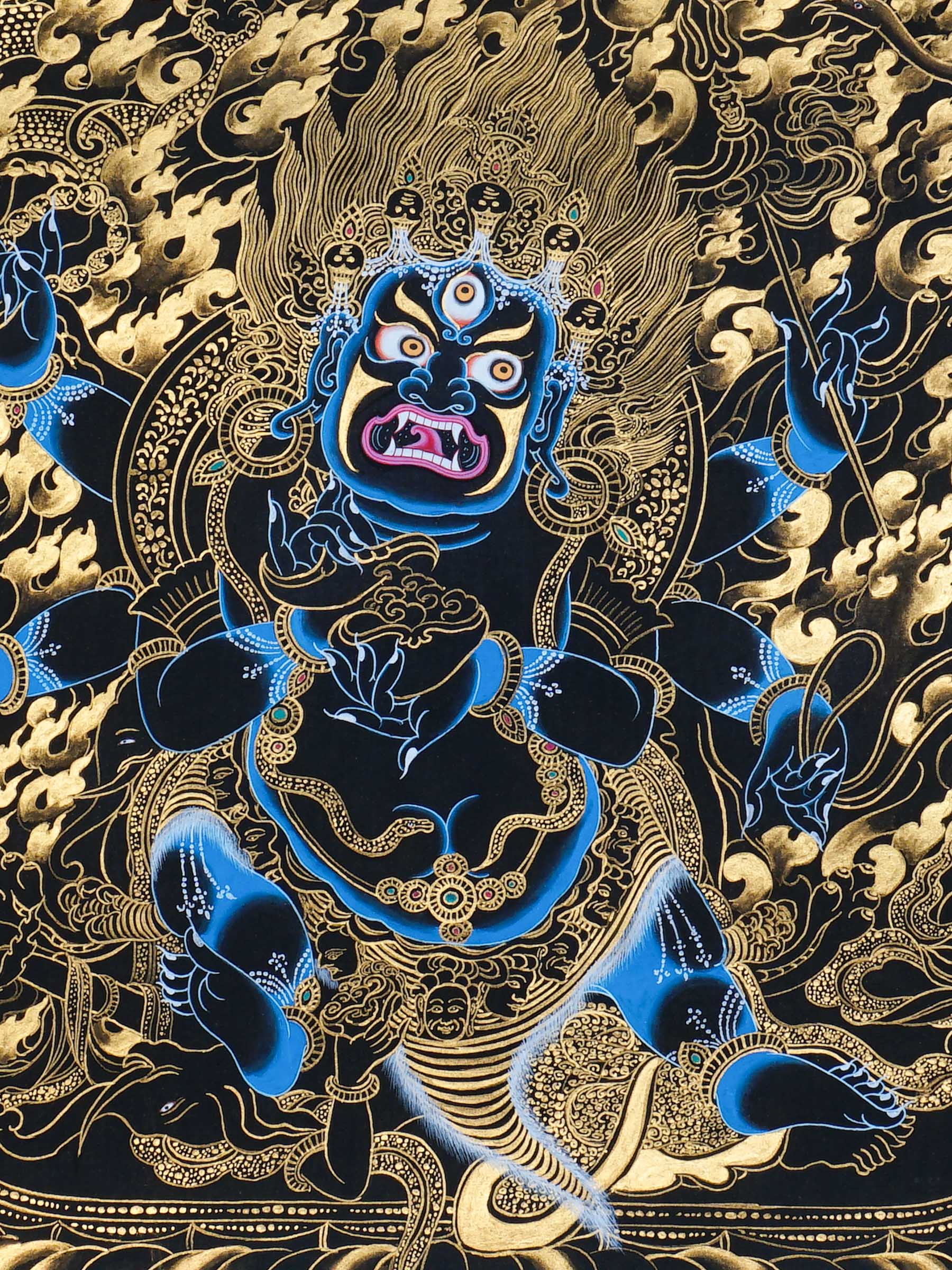 Mahakala thangka painting showing a wrathful blue Mahakala deity with multiple arms, flaming aura, gold clouds, dragon motif, and black background in traditional Tibetan Buddhist style.
