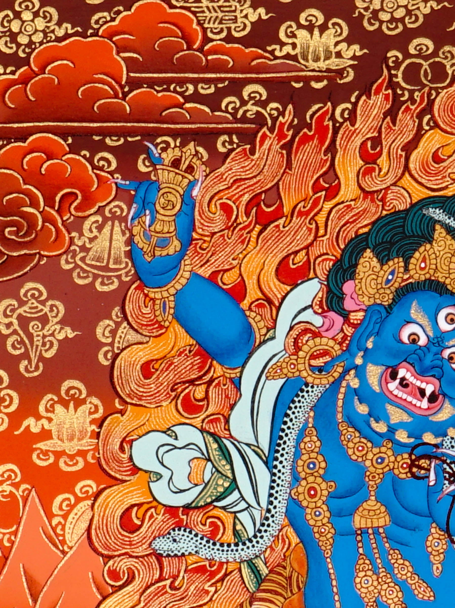 Vajrapani thangka painting showing a blue wrathful Tibetan Buddhist protector deity holding a raised vajra, surrounded by flames and seated on a lotus throne against a vivid orange-red background.