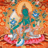 Green Tara Thangka Painting showing the Tibetan Buddhist goddess seated on a pink lotus throne with one leg extended, holding a lotus flower, surrounded by a radiant halo, sacred ornaments and red-gold background.