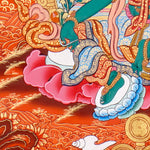 Green Tara Thangka Painting showing the Tibetan Buddhist goddess seated on a pink lotus throne with one leg extended, holding a lotus flower, surrounded by a radiant halo, sacred ornaments and red-gold background.