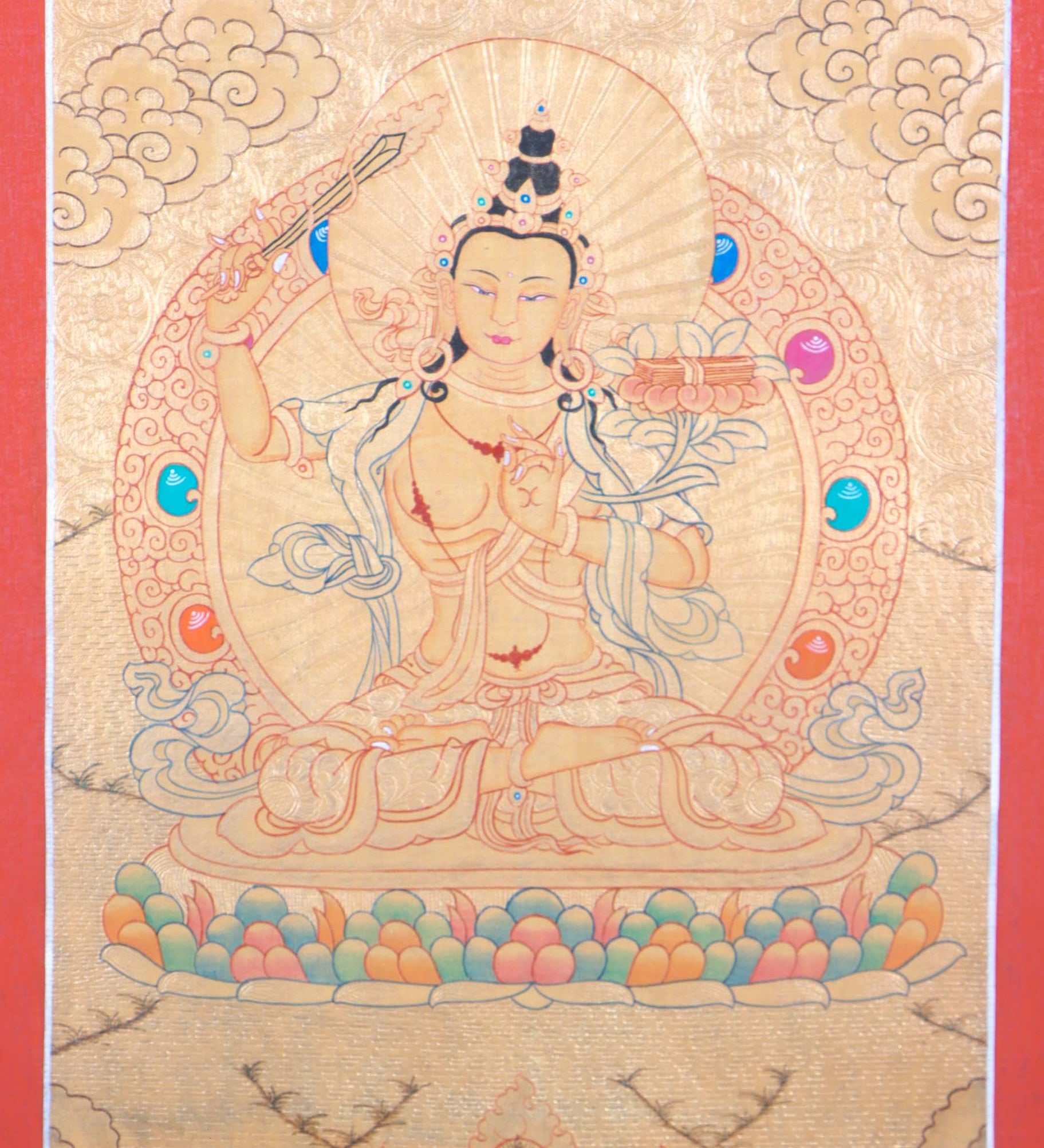 Buddhist Thangka are used as support for one's meditation practice. Manjushri is the Bodhisattva of transcendent wisdom. With the double-edged sword on his right hand he cuts through the illusion and with his left hand holds a lotus with book of Prajna Paramita.