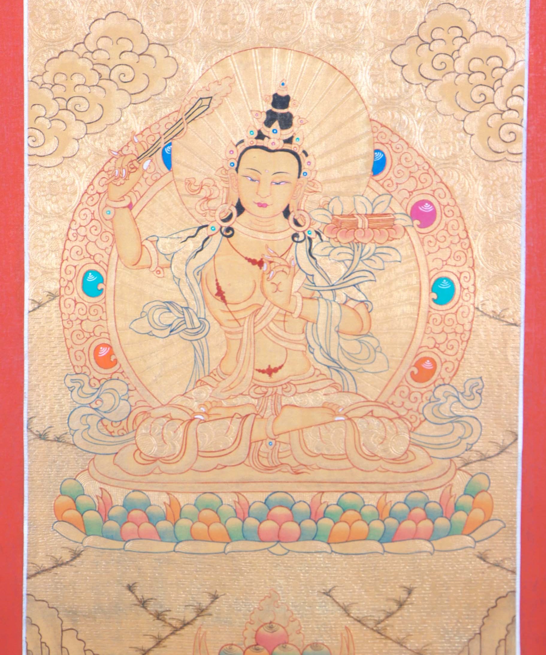 Buddhist Thangka are used as support for one's meditation practice. Manjushri is the Bodhisattva of transcendent wisdom. With the double-edged sword on his right hand he cuts through the illusion and with his left hand holds a lotus with book of Prajna Paramita.