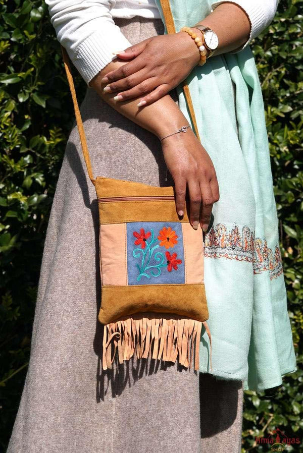 A small sling style, cross body bag with tassel/fringe at the bottom giving it a bohemian chic look.