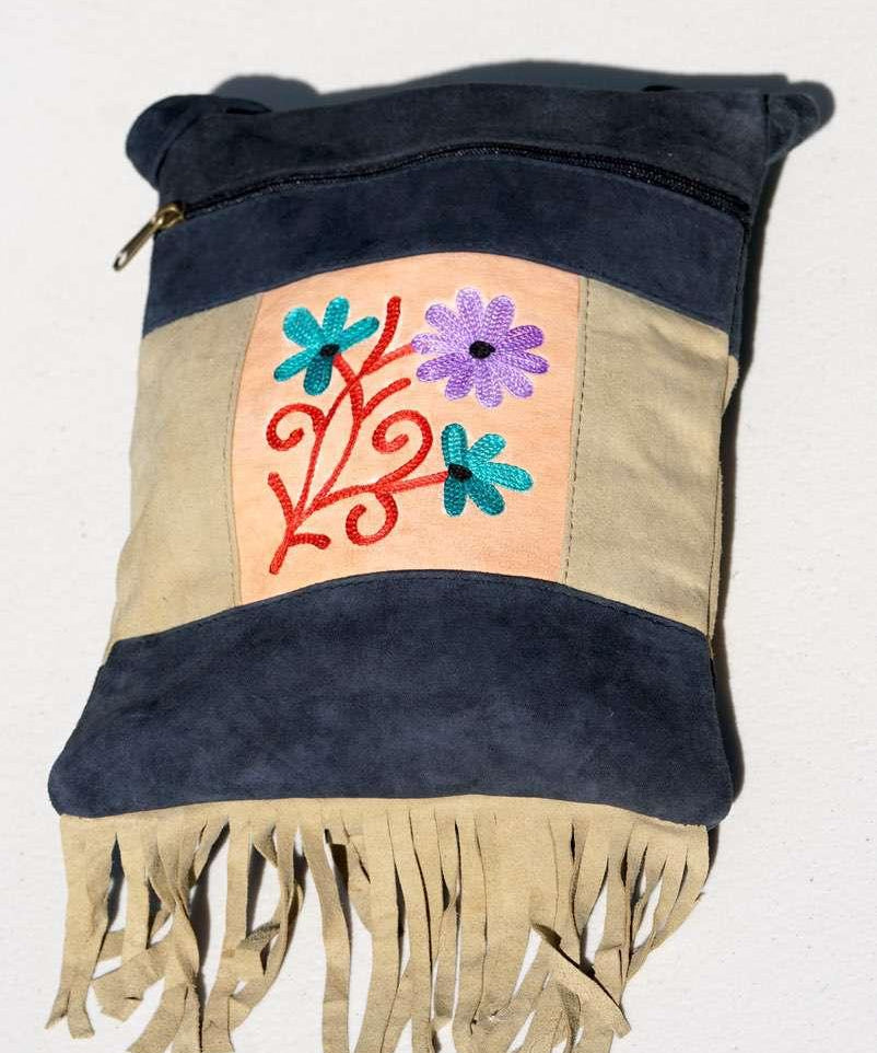 A small sling style, cross body bag with tassel/fringe at the bottom giving it a bohemian chic look.