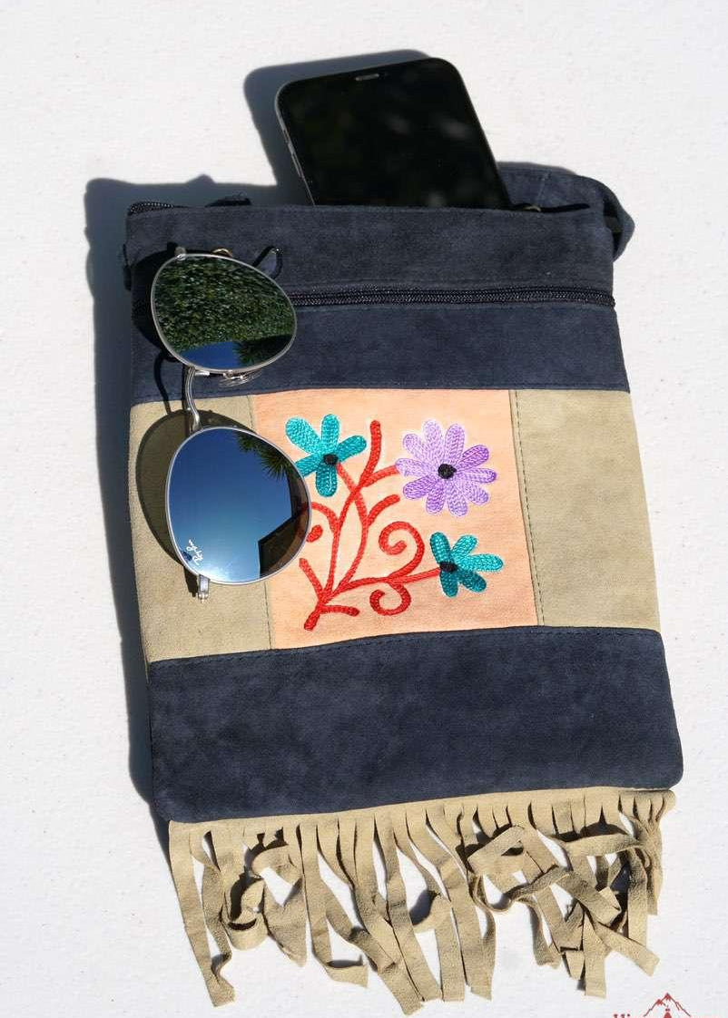 A small sling style, cross body bag with tassel/fringe at the bottom giving it a bohemian chic look.